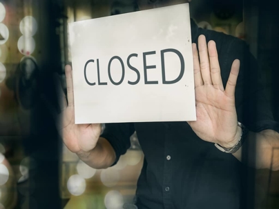 a business owner holding up a closed sign